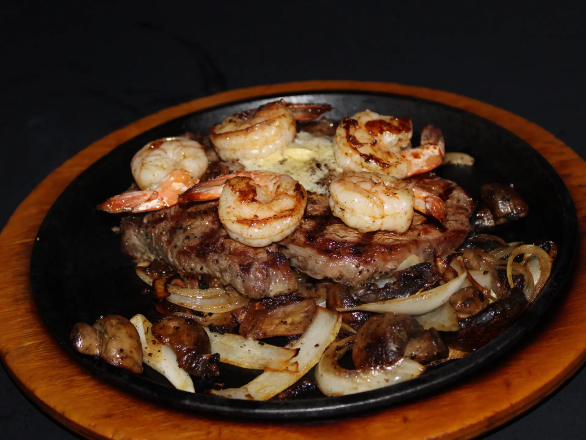 Surf and turf ribeye with grilled shrimp on a sizzling cast iron skillet at The Horseshoe Grill