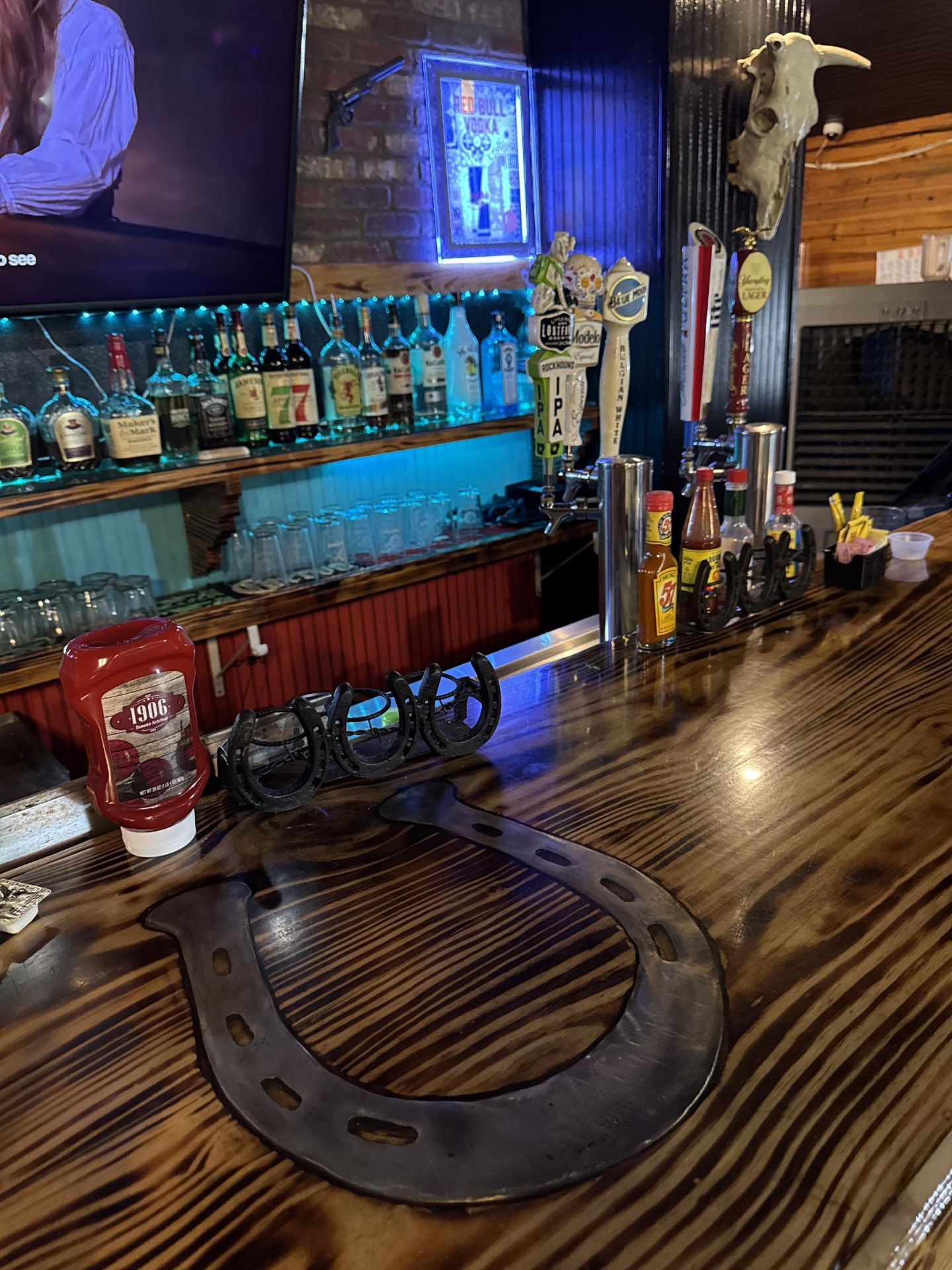 A horseshoe resting on the polished wood bar top at The Horseshoe Grill with beer taps and bottles behind it.